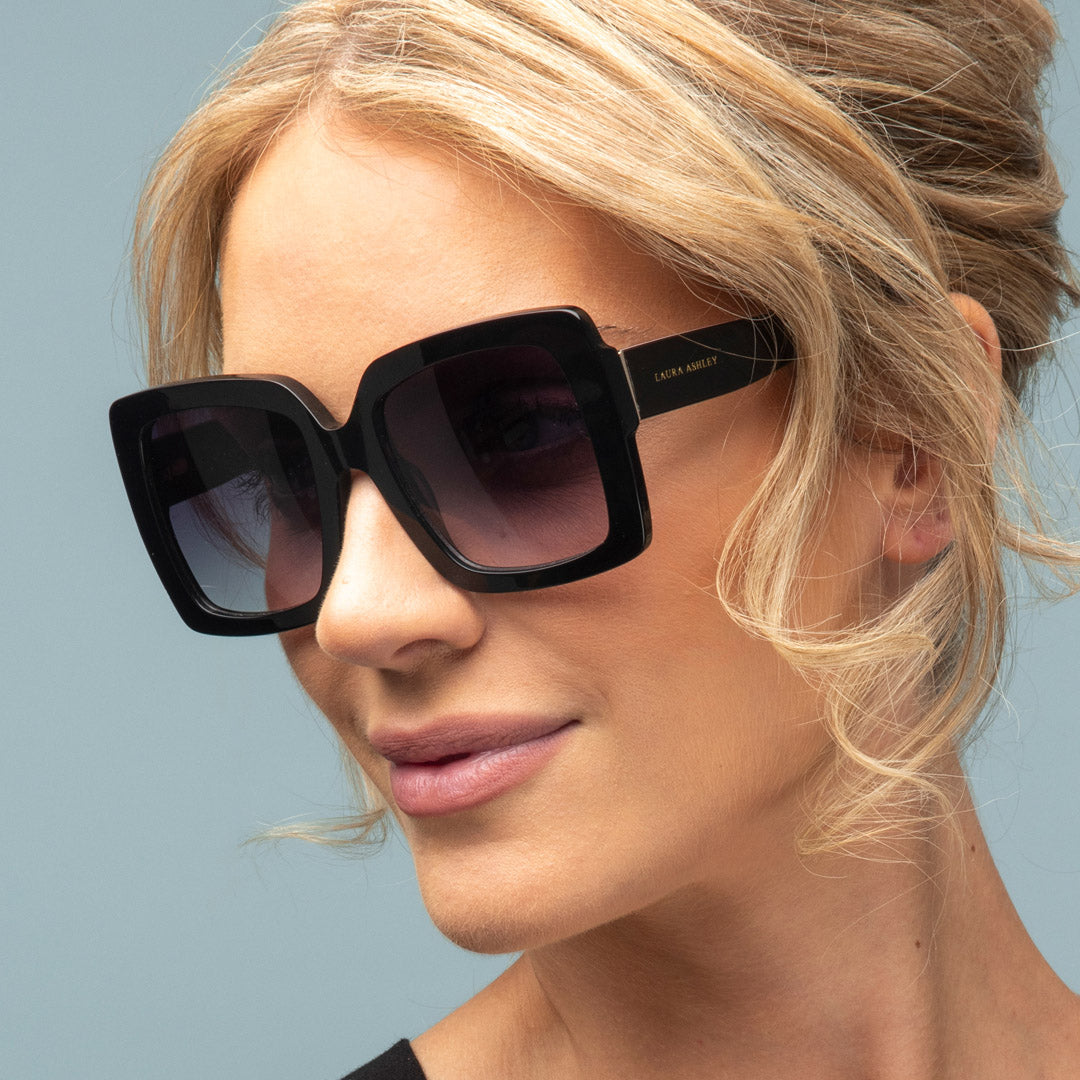 Woman wearing black sunglasses with a light blue background
