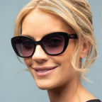 Woman wearing black sunglasses with a light gray background