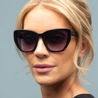 Woman wearing black sunglasses with a plain background