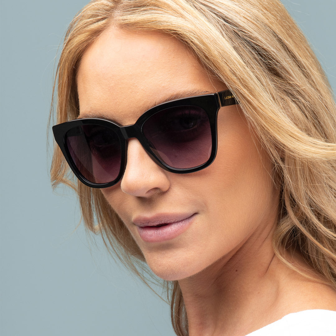 Woman wearing black sunglasses with a neutral background
