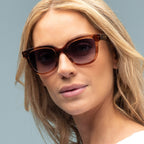 Woman wearing brown sunglasses with a neutral background