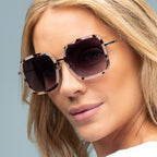 Close-up of a woman wearing stylish sunglasses with a neutral background