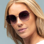 Woman wearing large sunglasses with a neutral background