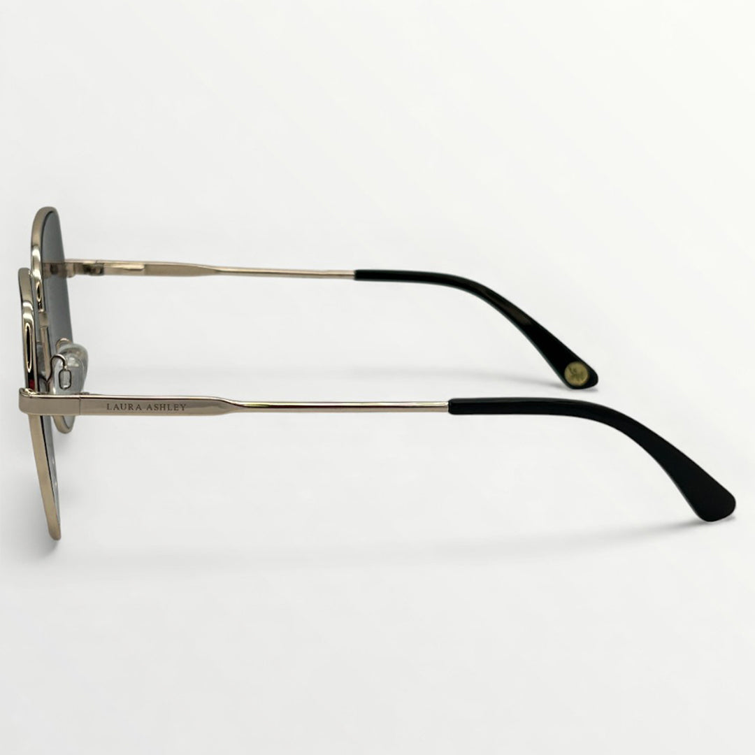Sunglasses with gold frame and black arms on a light gray background