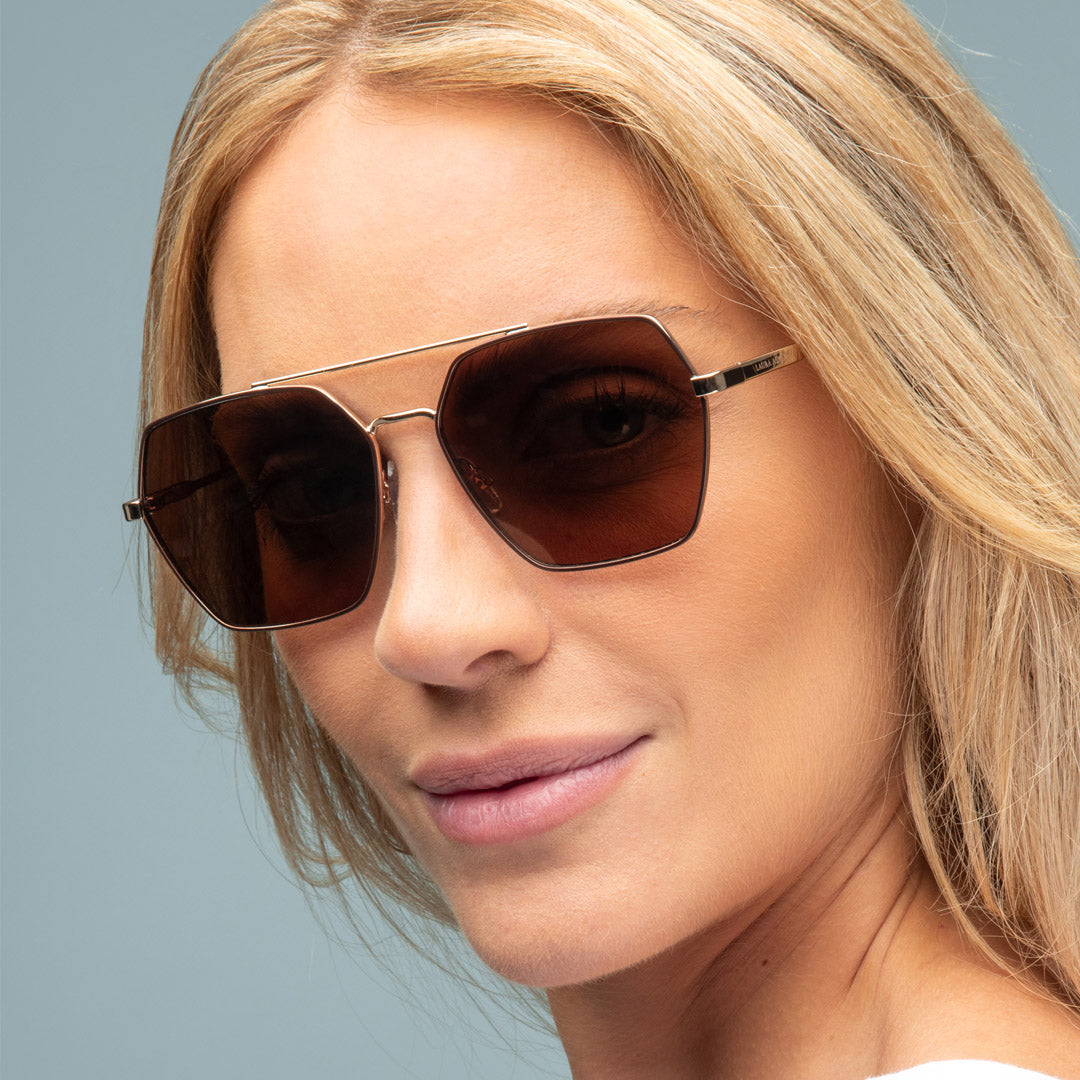 Close-up of a woman wearing sunglasses with a neutral background