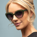 Woman wearing green sunglasses with a plain background