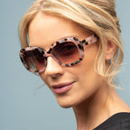 Woman wearing a pair of sunglasses with a light blue background