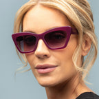 Woman wearing purple sunglasses against a light blue background